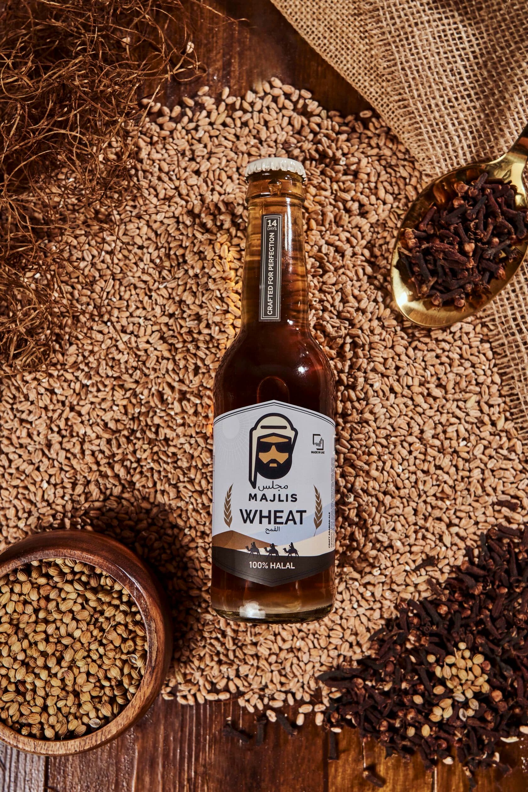 Majlis craft Arabian ale bottle on a flatlay of malted barley, cloves and burlap