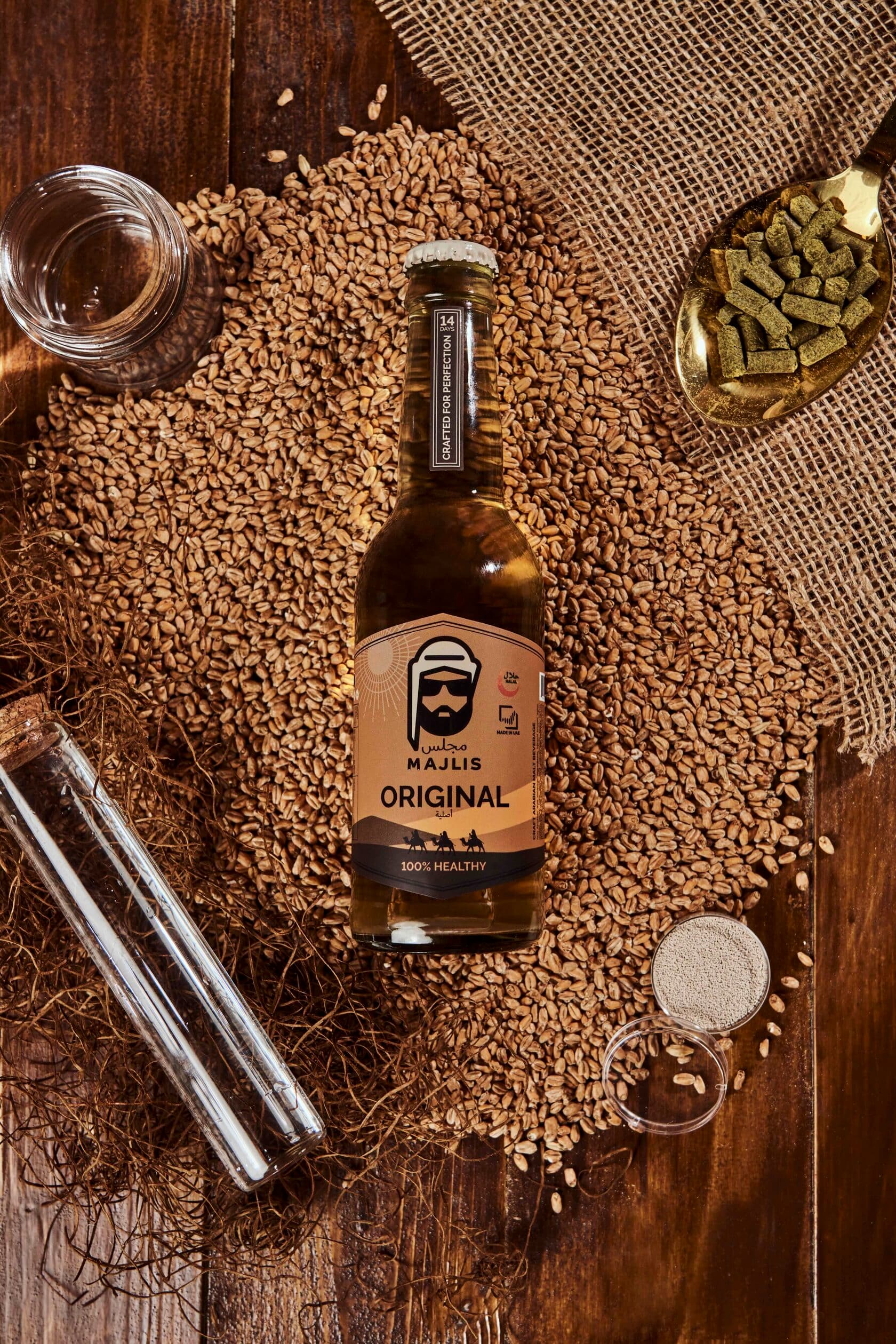 Majlis Original non-alcoholic craft Arabian ale bottle on a bed of malted barley